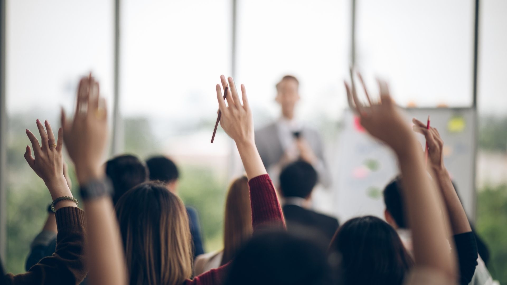 Teilnehmende melden sich im Seminar, Trainer steht am Flipchart