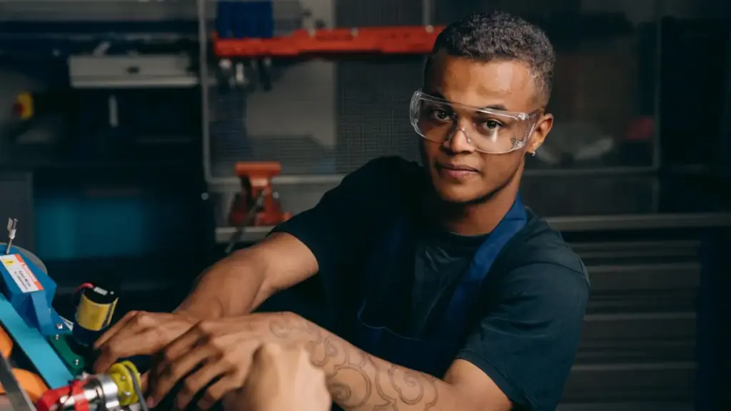 Junger Mann mit Schutzbrille an der Maschine